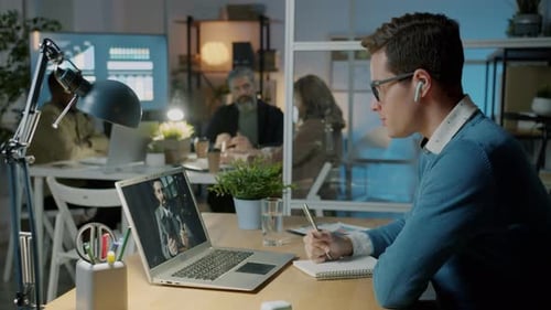 Businessmen Having Virtual Meeting Discussing Work Using Laptop and Wireless Earphones in Office at