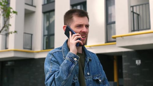 Handsome Caucasian Man with Serious Face Talking on the Mobile Phone About Business in the Center