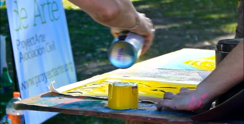 Adults Spray Painting Stencil Art in Urban Park
