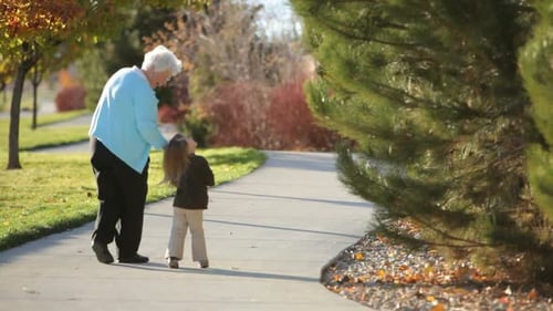 Adult and Child Walking Hand-in-Hand on Sidewalk