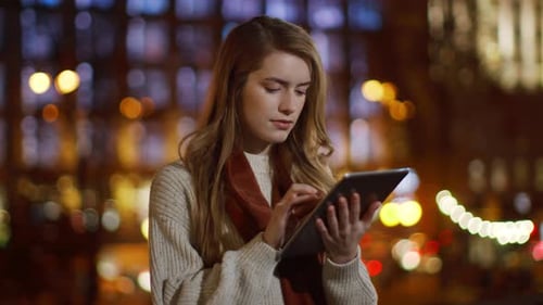 Young Woman Using Tablet at Night in City