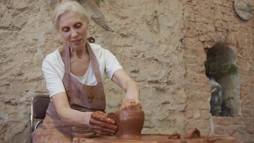 Une potière senior sculpte un pot en argile