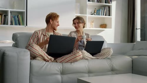 Happy Couple Working on Laptops on Couch At Home