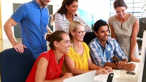 Smiling Colleagues Working Together at Computer in Office