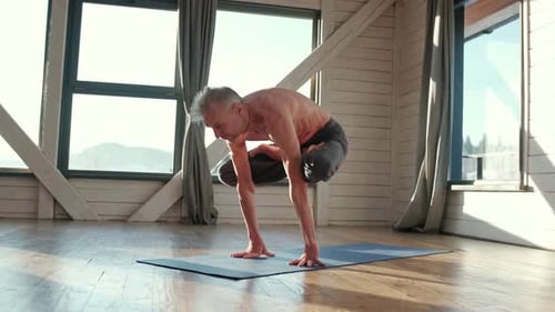Mature Man Practicing Advanced Yoga Pose Indoors