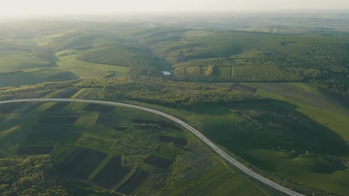 Aerial Drone View Flight Over Forest and Asphalt Road in Sunset Soft Light