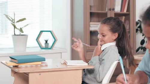 Young Girl Receives Help From Teacher in Classroom