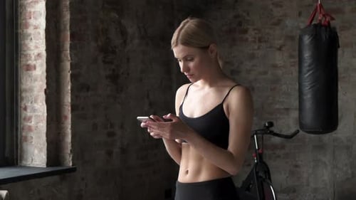 Woman Using Phone in Modern Home Gym