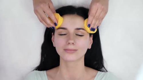 Woman receiving a relaxing facial with sponges