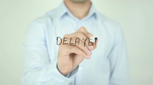Man Writes "DELAYED" on Transparent Surface