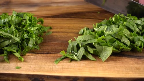 The cook cuts sorrel leaves on a wooden cutting board.