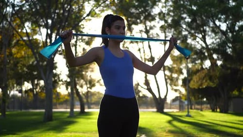 Woman Exercises with Resistance Band in Park