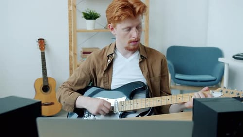 Red Haired Man Playing Electric Guitar at Home
