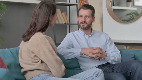 Pareja teniendo una conversación seria mientras está sentada en el sofá