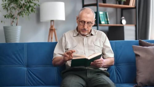 Senior Man Reading a Book on the Couch