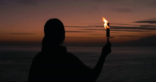 Silhouette with Torch at Twilight Ocean View