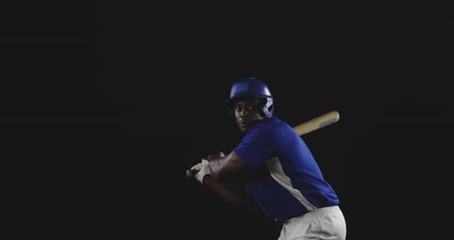 Baseball Player Hitting Ball with Bat in Studio