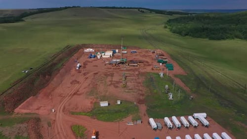 Öl und Gas: Eine Landplattform, eine Onshore-Bohranlage inmitten eines Reisfeldes, Luftaufnahme von einer Drohne