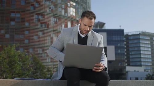Business Man Working on Laptop in City. Worker Browsing Internet on Computer