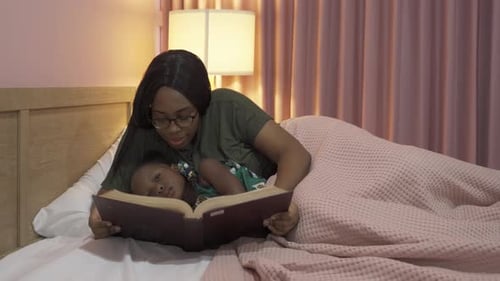 Mother Reading Bedtime Story to Daughter in Bedroom