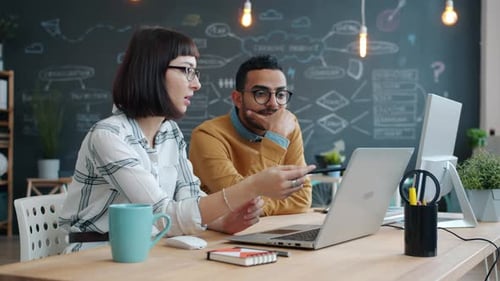 Creative Young People Woman and Man Sharing Ideas Talking Using Laptop in Office