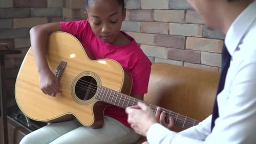 Child Learning Guitar with Teacher in Living Room