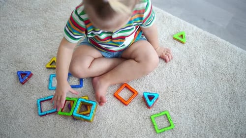 Child Assembles Colorful Shapes on the Rug