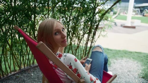 Young Woman Using Smartphone in Plant Gazebo