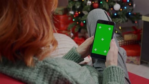 Woman Using Chroma Key Phone near Christmas Tree