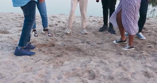 Shot of Legs of Six People Jumping Dancing in Sneakers Tennis Shoes on Sand on Beach Near Lake
