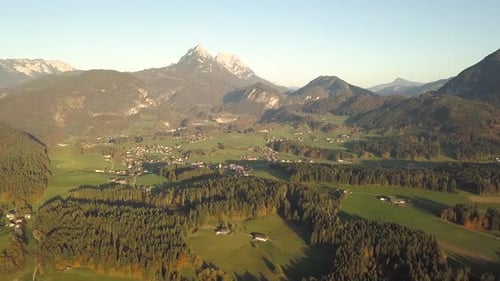 Aerial view of green meadows with villages and forest in austrian Alps mountains