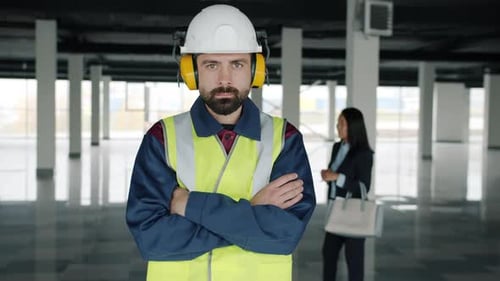 Portrait of Maintenance Specialist Standing Inside New Industrial Building While Businesspeople