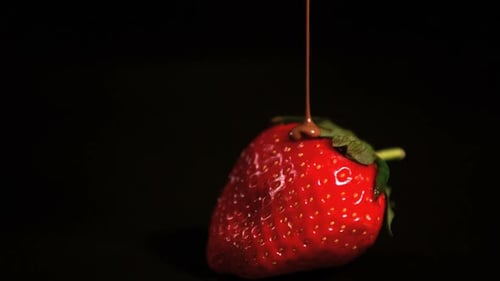 Melted chocolate pouring over strawberry
