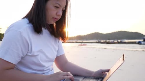 Freelancer Asian woman using laptop online working on the beach