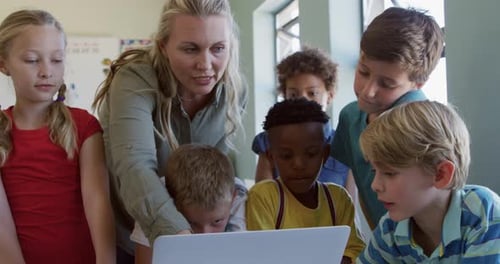 Lehrerin und Gruppe von Kindern mit Laptop in der Klasse
