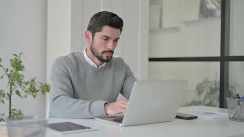 Stressed Man Typing on Laptop in Office