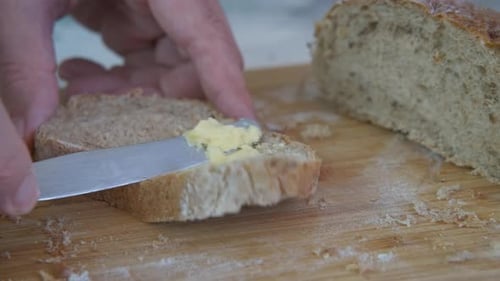 Buttering a Slice of Grain Bread Close Up
