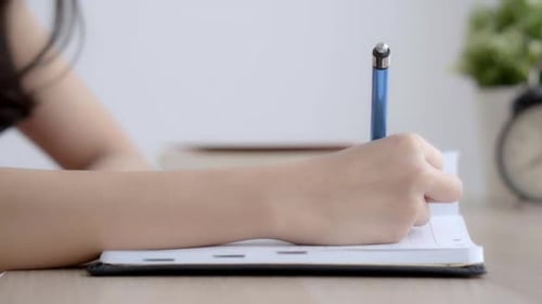 Woman Writing in Notebook with Blue Pen