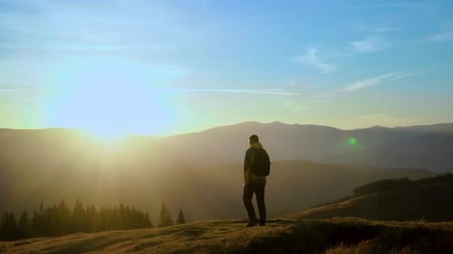 Hiker Walking on Mountain Top at Sunrise