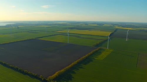 Wind Turbines Spinning Above Green and Yellow Fields