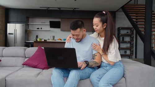 Couple Using Laptop Together on Couch at Home