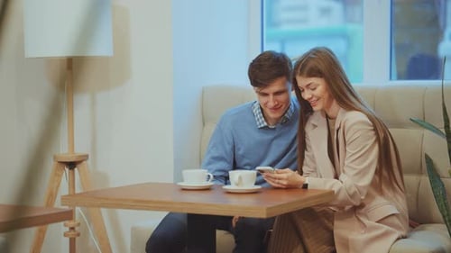 Loving Couple Looking at Smartphone in Cafe