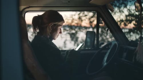 Woman Using Phone Inside of a Parked Van