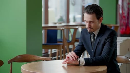 Anxious Serious Caucasian Businessman Checking Time on Watch Sitting in Restaurant