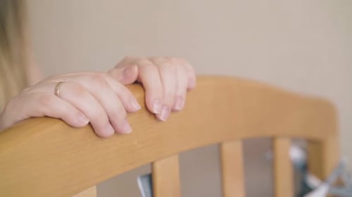 Mother Gently Looks at Baby in Crib