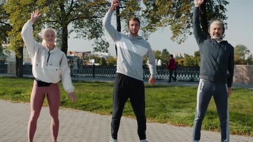 Group of People Men and Woman Exercising Outdoors in City Park Enjoying Summer Day