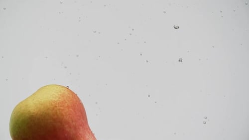 Ripe Fruits Red and Yellow Pears Falling Into Water with Splash and Bubbles White Background