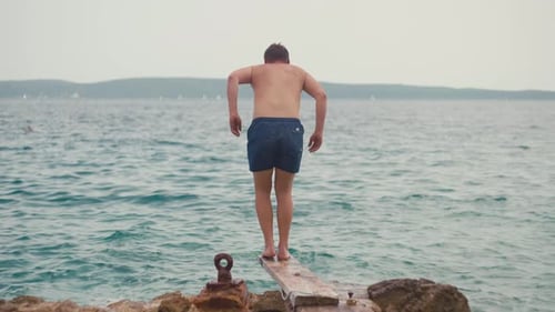 Lifestyle Zeitlupenvideo eines Mannes, der von einem Pier ins Meerwasser springt