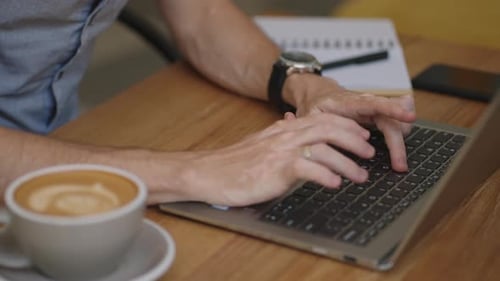 Person Typing on Laptop in Coffee Shop
