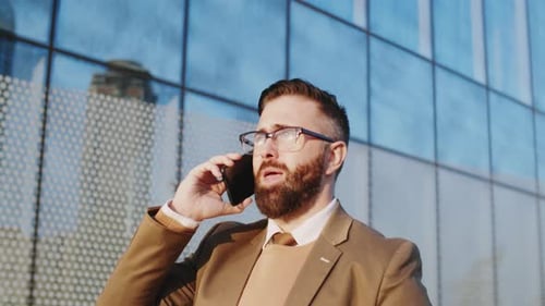 Man in Suit Talking on Cellphone Outside Office